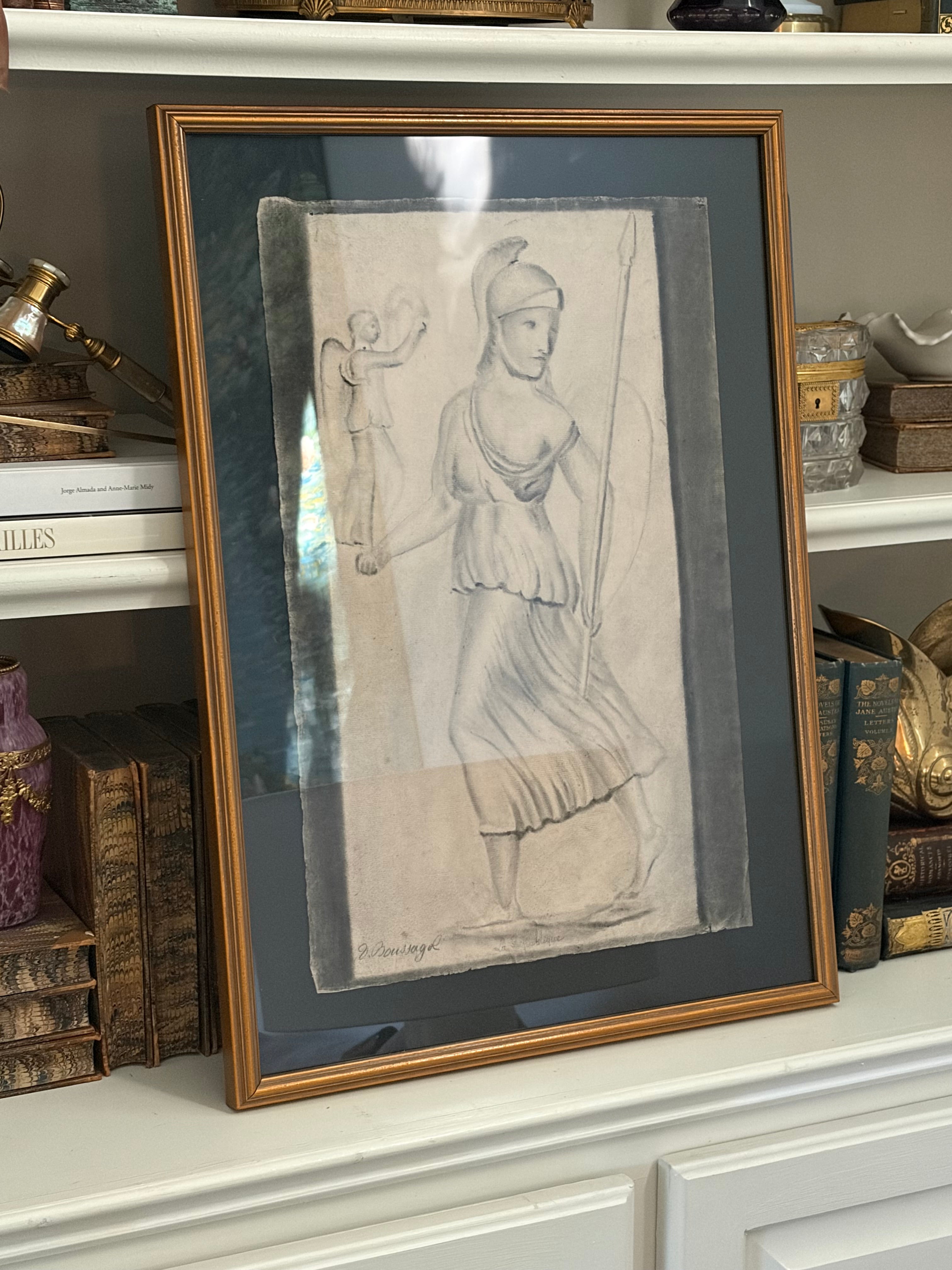 Antique French charcoal drawing of Athena in a gilt frame, displayed on a shelf among books and decorative objects