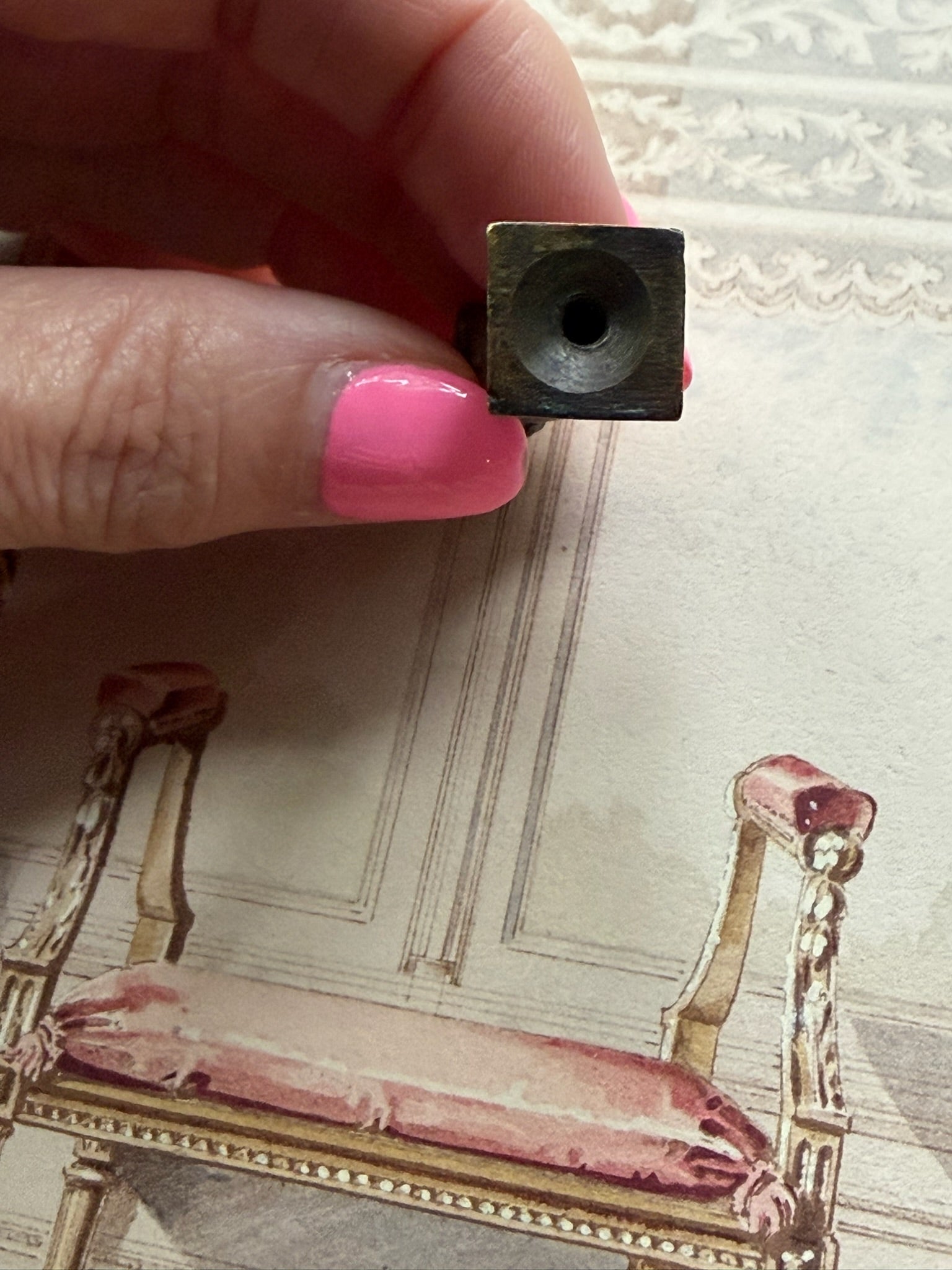 Close-up of the antique bronze figural's square base showing the drilled mounting hole, indicating prior use as a finial or mount